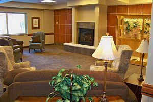 Common area with chairs, couches and a fire place. 